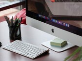 Un iMac posé sur un bureau, avec le dock macOS visible à l'écran et un clavier Apple devant