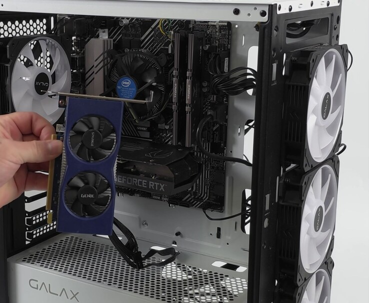 Une main tenant une carte graphique Intel Arc A380 à côté d'un PC équipé d'une carte Nvidia GeForce RTX 3060, préparée pour une configuration double-GPU avec Lossless Scaling (Source de l'image : ETA PRIME via YouTube)