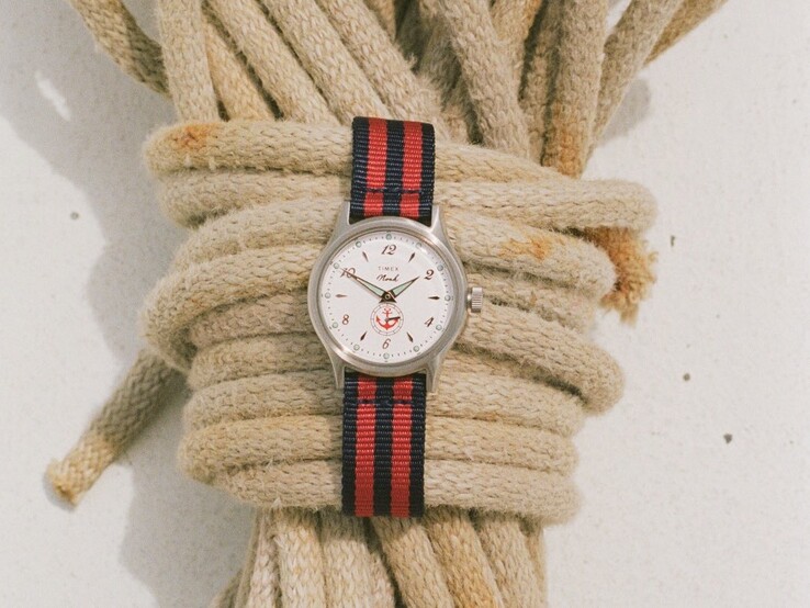Montre Noah x Timex MK1 Anchor avec un boîtier argenté de 36 mm, un cadran blanc, un motif d'ancre et un bracelet en tissu rayé bleu marine et rouge.