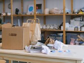 Boîte en carton et sacs en papier sur une table en bois dans un bureau avec des étagères