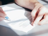 Une main signe un document avec un stylo à bille bleu