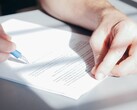 Une main signe un document avec un stylo à bille bleu