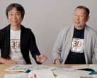 Une capture d'écran de Shigru Miyamoto et Tezuka Takashi portant des t-shirts du 30e anniversaire de Super Mario Bros