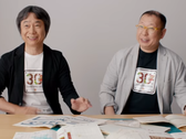 Une capture d'écran de Shigru Miyamoto et Tezuka Takashi portant des t-shirts du 30e anniversaire de Super Mario Bros