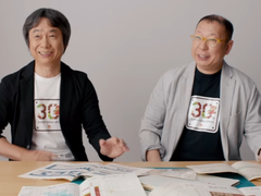 Une capture d'écran de Shigru Miyamoto et Tezuka Takashi portant des t-shirts du 30e anniversaire de Super Mario Bros