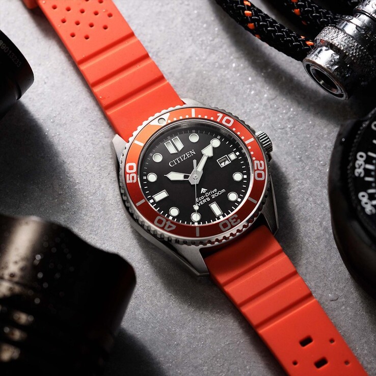 Montre de plongée Citizen Promaster Marine BN0268-01E, dotée d'un cadran noir, d'une lunette orange et d'un bracelet orange, photographiée sur une surface texturée.