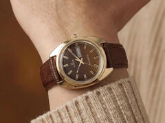 Timex Q 1978 Day and Date avec un cadran fumé brun et un boîtier doré, présentée au poignet avec un bracelet en cuir brun.