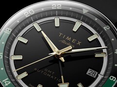 Gros plan du cadran noir de la Timex Atelier GMT Première M1a, avec ses aiguilles dorées, ses index horaires luminescents, son guichet de date et son anneau GMT 24 heures noir et vert.