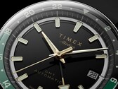 Gros plan du cadran noir de la Timex Atelier GMT Première M1a, avec ses aiguilles dorées, ses index horaires luminescents, son guichet de date et son anneau GMT 24 heures noir et vert.