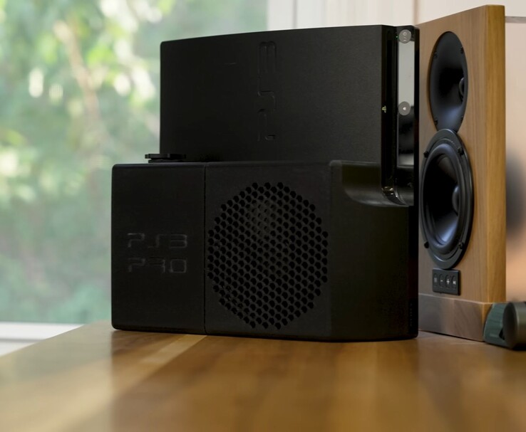 PlayStation 3 refroidie à l'eau avec un boîtier arrière noir "PS3 Pro" imprimé en 3D à côté d'un haut-parleur en bois. (Source de l'image : Zac Builds via YouTube)