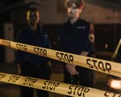 Deux policiers se tenant debout la nuit derrière un ruban jaune portant l’inscription Stop