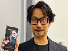 Hideo Kojima montrant une affiche de Physint sur son téléphone