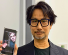 Hideo Kojima montrant une affiche de Physint sur son téléphone