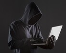 Un pirate informatique cagoulé utilisant un ordinateur portable sur un fond sombre.