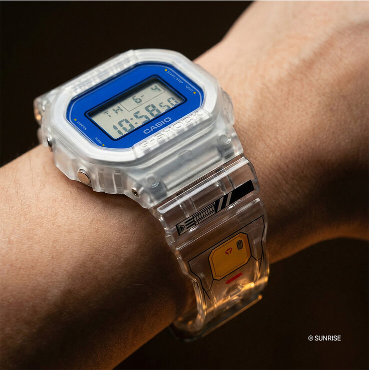 Casio G-Shock x Mobile Suit Gundam DW-5600GM26-7DR portée au poignet, avec un boîtier et un bracelet en résine transparente, une lunette bleue et des graphismes inspirés de Gundam sur le bracelet.