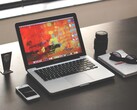 MacBook Pro posé sur un bureau sombre, à côté d’un smartphone, de lunettes et d’un carnet