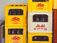 Caisses en plastique jaune et blanc empilées, remplies de bouteilles de bière Asahi, avec un texte japonais et des logos rouges. (Source de l'image : Photo par Alazne Lazcano via Pexels)