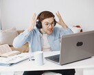 Homme portant un casque et levant les mains de frustration devant un ordinateur portable