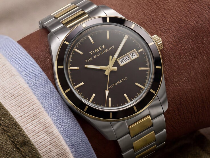 Montre Timex Waterbury Heritage Automatic bicolore à cadran noir, portée au poignet, présentant son affichage jour-date et ses finitions dorées.