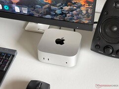Un Mac mini Apple M6 posé sur un bureau dans une configuration de jeu, avec un écran, un clavier, une souris et des haut-parleurs.