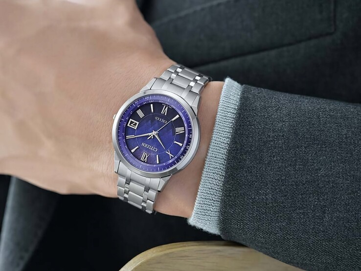 La Citizen Exceed CB1140-79L portée au poignet, dévoilant son cadran bleu, son boîtier argenté et son bracelet intégré en titane sur fond de veste sombre.