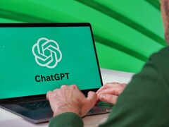 Un homme tape sur un ordinateur portable dont l'écran affiche le logo ChatGPT