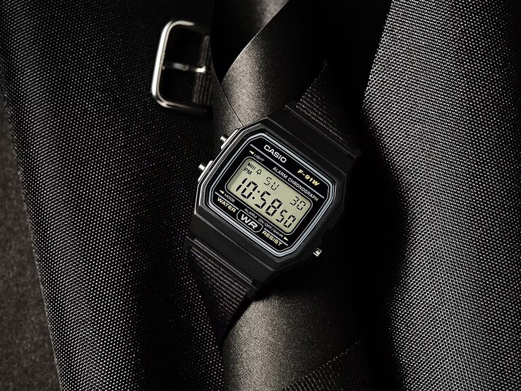 Montre numérique Casio F-91WF-1A dotée d'un boîtier noir, d'un bracelet en tissu tressé noir et de détails argentés, photographiée sur un fond sombre texturé.