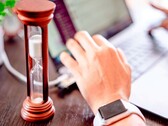 Un sablier à côté d’une main posée sur le clavier d’un ordinateur portable
