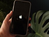 Une main tient un iPhone ; le logo Apple et une barre de progression s'affichent à l'écran.