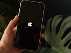 Une main tient un iPhone ; le logo Apple et une barre de progression s'affichent à l'écran.
