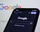 Smartphone affichant la page de recherche Google devant un écran avec le logo Google