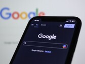 Smartphone affichant la page de recherche Google devant un écran avec le logo Google
