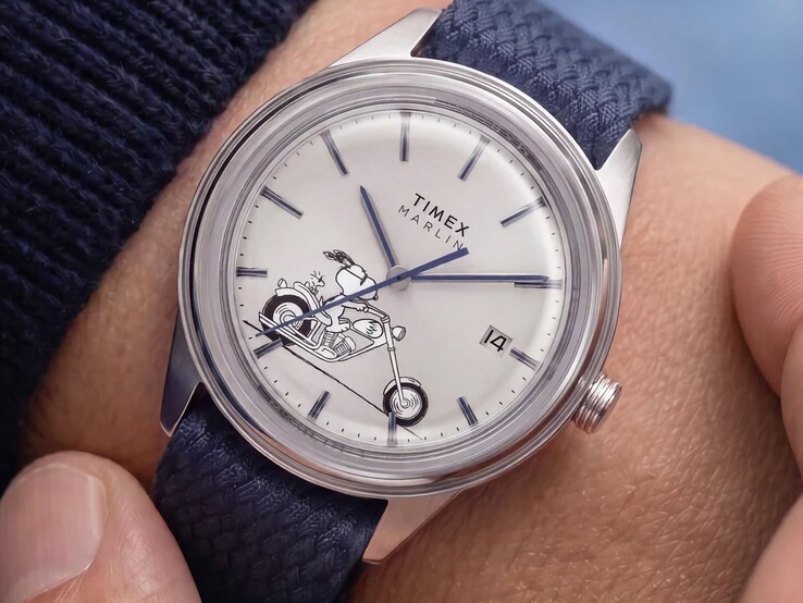 La montre Peanuts x Timex Marlin Jet Automatic Easy Rider portée au poignet, représentant Snoopy à moto sur le cadran blanc argenté, avec des index et des aiguilles bleus, ainsi qu’un bracelet en tissu tissé bleu.