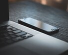 Un smartphone posé à côté d’un ordinateur portable ouvert sur un bureau sombre