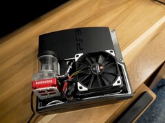 PlayStation 3 refroidie à l'eau avec une pompe SysCooling rouge et un grand ventilateur noir monté à l'intérieur du boîtier, placé sur un bureau en bois (Source de l'image : Zac Builds via YouTube)