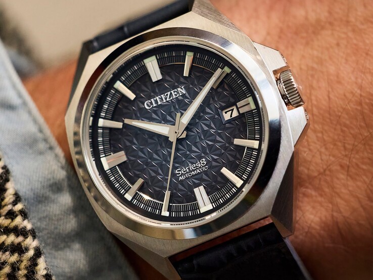 Montre automatique Citizen Série 8 831, dotée d’un cadran géométrique orange brûlé et marron, d’un boîtier et d’une lunette dorés, ainsi que d’un bracelet intégré à maillons en H dorés, portée au poignet.