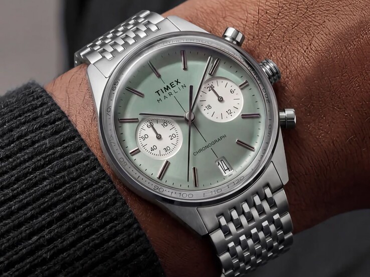 Chronographe Timex Marlin Jet doté d’un cadran vert sauge et d’un bracelet en acier inoxydable, porté au poignet, mettant en valeur son verre bombé et le profil arrondi et rétro-futuriste de son boîtier.