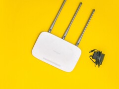 Routeur Wi-Fi blanc doté de trois antennes et d'un bloc d'alimentation, sur fond jaune