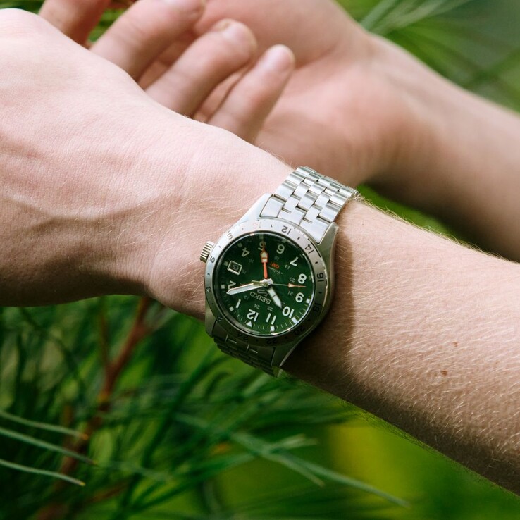 Vue de face de la Seiko 5 Sports Field GMT HDB001, dotée d'un cadran vert, d'une lunette fixe en acier inoxydable graduée sur 24 heures, d'une aiguille GMT orange et d'un bracelet en acier à cinq maillons.