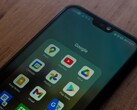 Un smartphone posé sur un bureau en bois, avec un dossier de l'application Google ouvert
