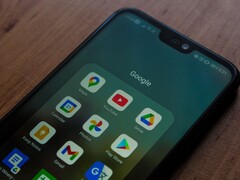 Un smartphone posé sur un bureau en bois, avec un dossier de l'application Google ouvert
