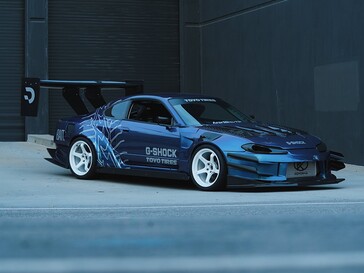 Une voiture de drift bleue arborant des visuels G-Shock et Toyo Tires, garée devant un bâtiment industriel.
