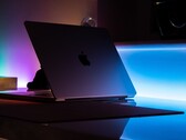 Un MacBook à demi-ouvert dans une pièce sombre, la lumière s'échappant par l'interstice et se répandant sur le bureau