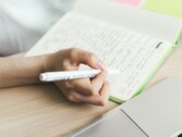 Une personne prend des notes dans un cahier à côté d'un ordinateur portable ouvert