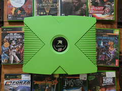 Une Xbox de couleur verte avec 10 titres Xbox rétro illustrés
