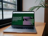 Un ordinateur portable posé sur un bureau près d'une fenêtre, avec le site web OpenAI ChatGPT ouvert à l'écran