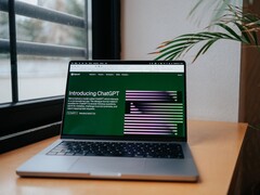 Un ordinateur portable posé sur un bureau près d'une fenêtre, avec le site web OpenAI ChatGPT ouvert à l'écran