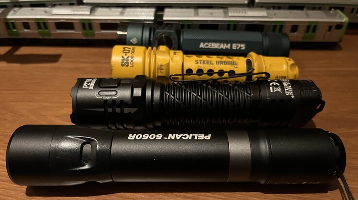 La SK-07 jaune de Loop Gear comparée à l'Acebeam E75 (à l'arrière), à la Nitecore P27i et à la Pelican 5050R