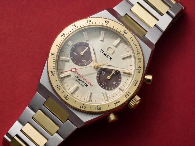 Gros plan sur la montre Timex Q Timex Continental Chronograph TW2Y92300 portée au poignet, montrant son cadran doré, ses sous-cadrans marron, sa lunette tachymétrique et son bracelet bicolore en acier inoxydable.