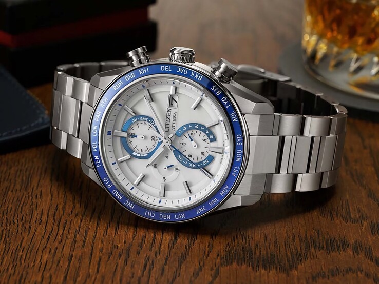 Chronographe Citizen Attesa AT8297-51L posé sur une table en bois, avec son cadran bleu marine, ses détails en or rose et sa lunette noire à heure universelle.